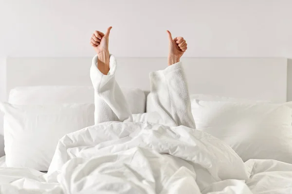 Handen van vrouw liggend in bed en tonen duimen omhoog — Stockfoto