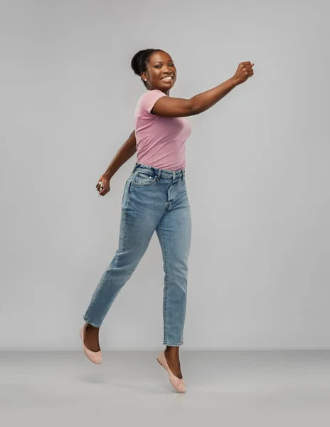 Šťastný africký americký žena jumping přes šedý — Stock fotografie