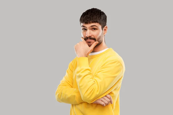 Думающий молодой человек в желтой свитерке — стоковое фото
