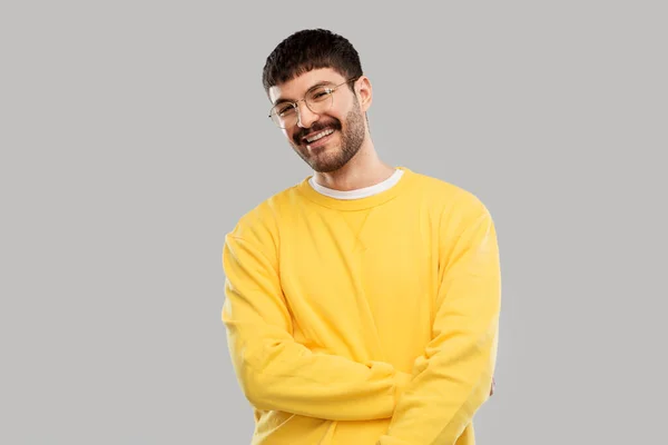 Mosolygós fiatalember szemüvegben és sárga pulóverben — Stock Fotó