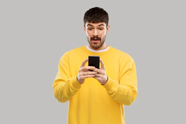 Förvånad ung man med smartphone — Stockfoto