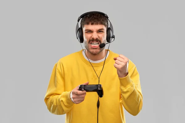 Hombre con auriculares y gamepad jugando videojuego — Foto de Stock