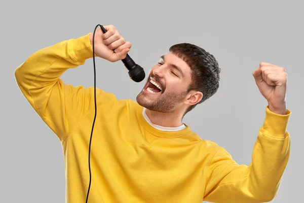 Hombre en sudadera amarilla con micrófono cantando —  Fotos de Stock