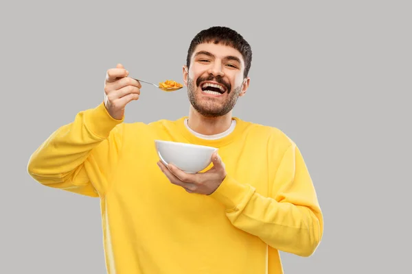 Šťastný usmívající se mladý muž jíst cereálie — Stock fotografie
