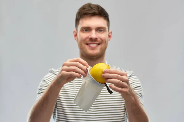 Hymyilevä mies sitruunalla uudelleenkäytettävässä kangaspussissa — kuvapankkivalokuva