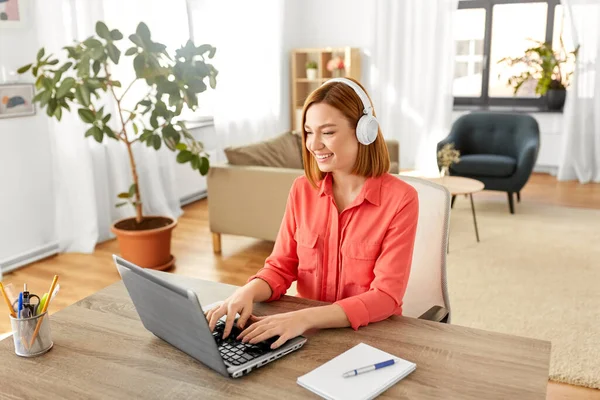 Mujer en auriculares con portátil trabajando en casa — Foto de Stock