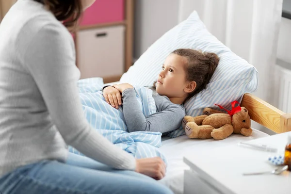 Mother and sick daughter lying in bed at home — Stock Photo, Image