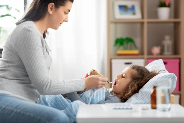 Moeder geeft hoestsiroop aan zieke dochter — Stockfoto