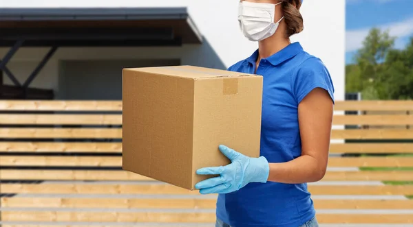 Entrega mulher no rosto máscara segurando caixa de parcela — Fotografia de Stock
