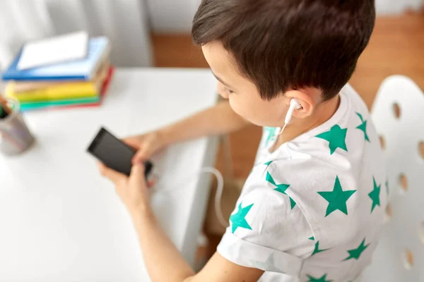 Fiú fülhallgatóval és okostelefonnal otthon — Stock Fotó