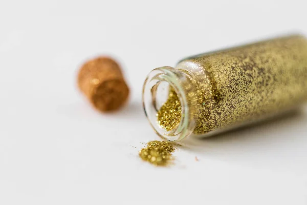 Golden glitters poured from small glass bottle — Stock Photo, Image