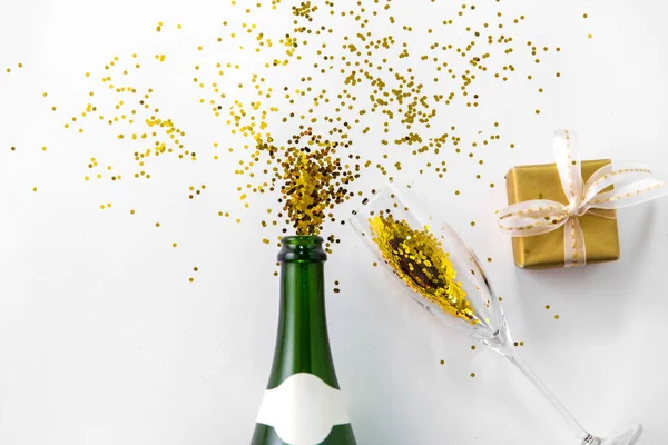 Bouteille de champagne, verre, cadeau et paillettes dorées — Photo