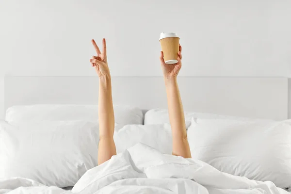 Mujer con café acostado en la cama mostrando paz —  Fotos de Stock