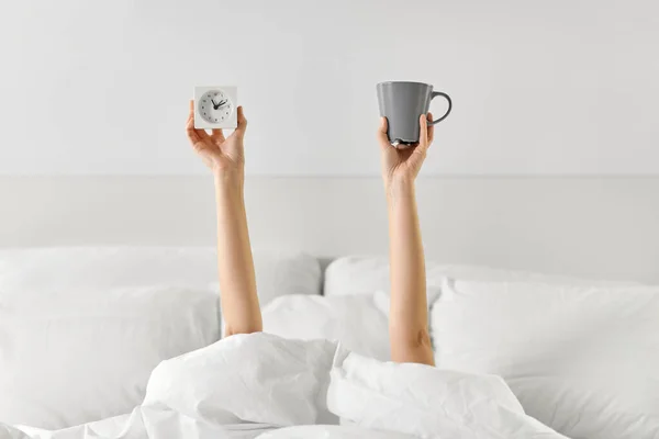 Mujer con café y despertador tumbado en la cama —  Fotos de Stock