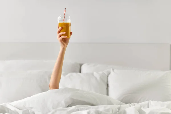 Mano de mujer acostada en la cama con taza de jugo —  Fotos de Stock