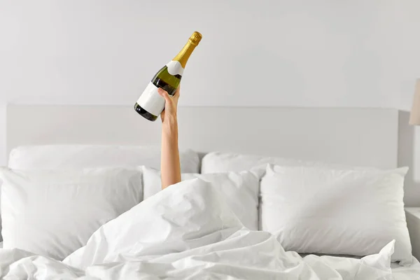 Hand einer Frau, die mit Champagner im Bett liegt — Stockfoto