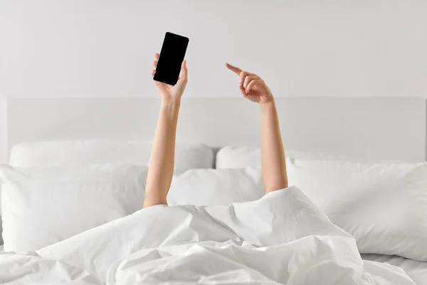 Hands of woman lying in bed with smartphone — Stock Photo, Image