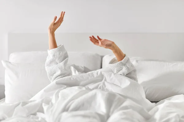 Mãos de mulher deitada na cama e alongamento — Fotografia de Stock