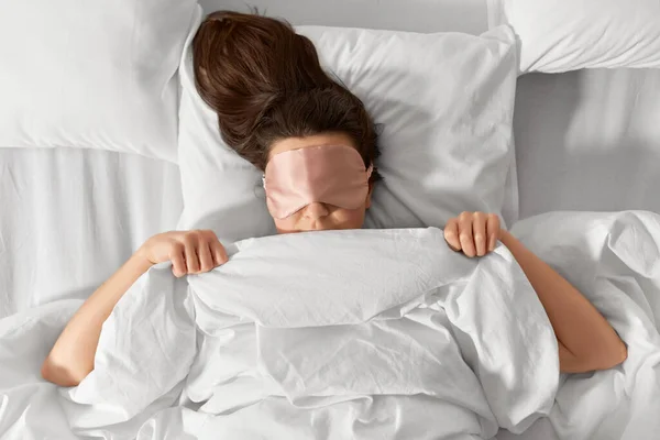 Mulher com máscara de dormir olho na cama sob cobertor — Fotografia de Stock
