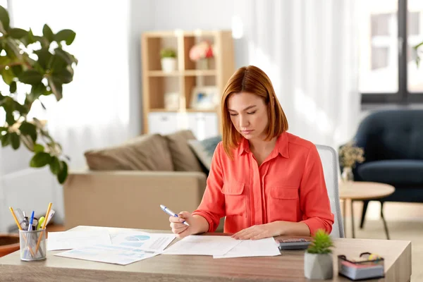 Kvinna med miniräknare och papper arbetar hemma — Stockfoto