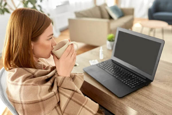 Больная женщина с чаем с видеозвонком на ноутбуке — стоковое фото
