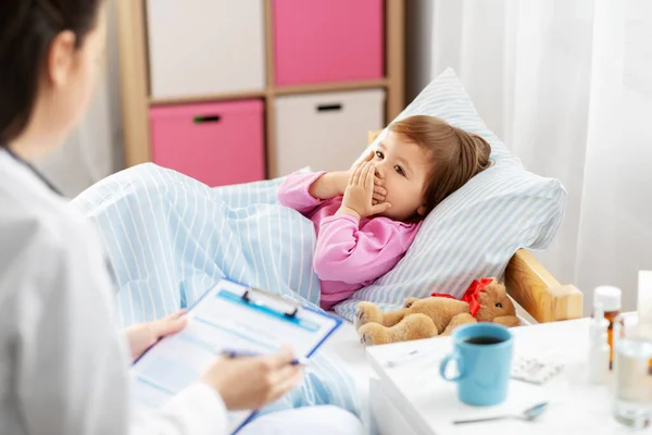 Doctor and ill coughing little girl in bed at home — Stock Photo, Image