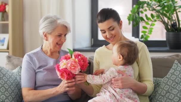 Anya és lánya virágot adnak a nagymamának — Stock videók