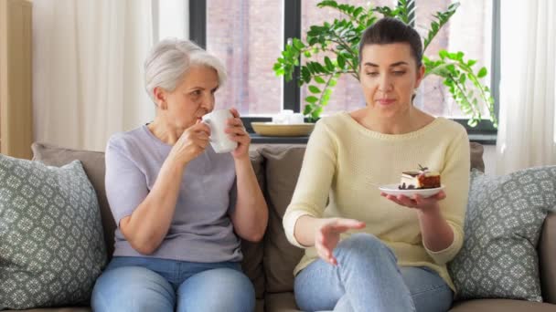 Vieja madre e hija adulta comiendo pastel en casa — Vídeos de Stock
