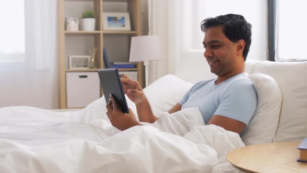 Hombre indio feliz con la tableta PC en la cama en casa — Vídeos de Stock