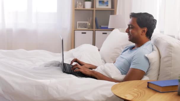 Szczęśliwy Indianin człowiek z laptopem w łóżku w domu — Wideo stockowe