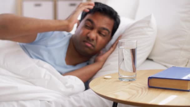 Человек в постели с лекарством и стаканом воды — стоковое видео