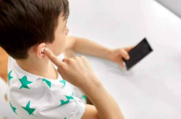 Fiú fülhallgatóval és okostelefonnal otthon — Stock Fotó