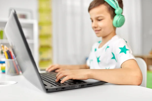 Jongen in hoofdtelefoon spelen video game op laptop — Stockfoto