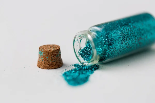 Purpurina azul vertida de una pequeña botella de vidrio —  Fotos de Stock