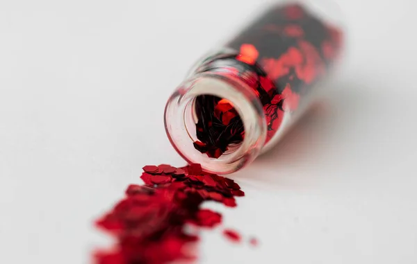 Червоні блискітки, наливаються з маленької скляної пляшки — стокове фото