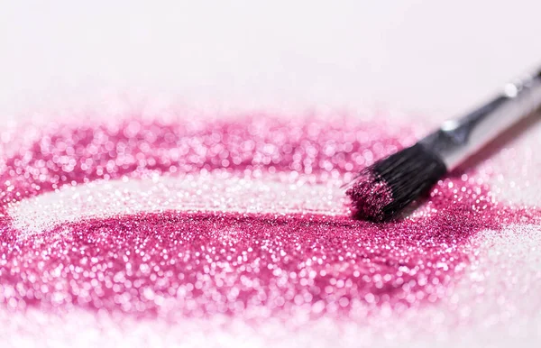 Make-up penseel maken beroerte op roze glitters — Stockfoto