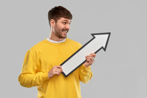 Smiling man holding big arrow pointing to right — Stock Photo, Image