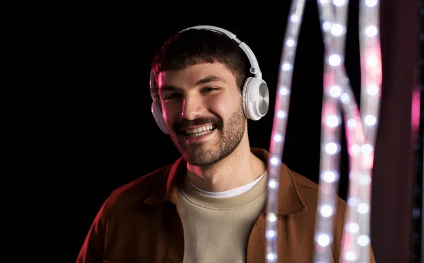 Mann mit Kopfhörer über Neonlicht eines Nachtclubs — Stockfoto