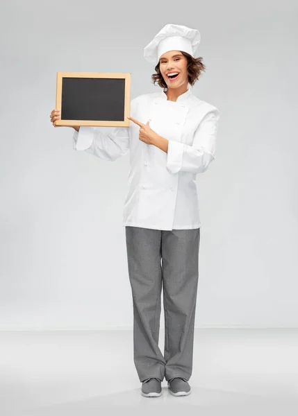 Sorridente chef donna con lavagna nera in mano — Foto Stock
