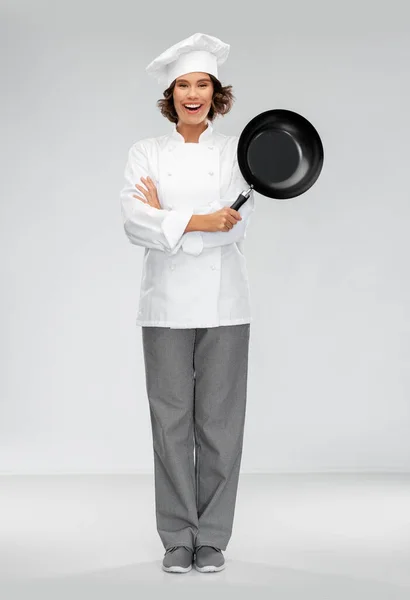 Glimlachende vrouwelijke chef in toque met koekenpan — Stockfoto