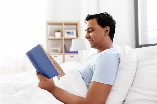 Gelukkig indiaans man lezen boek in bed thuis — Stockfoto