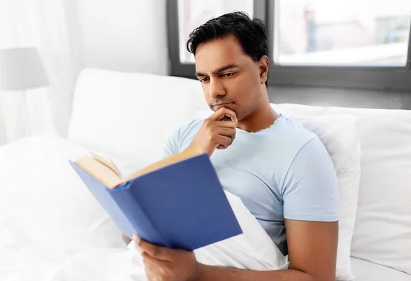 Hombre indio leyendo libro en la cama en casa —  Fotos de Stock