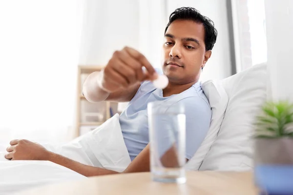 Человек в постели бросает лекарство в стакан с водой — стоковое фото