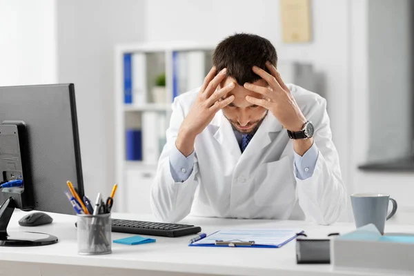 Stressed male doctor with clipboard at hospital — Stock Photo, Image