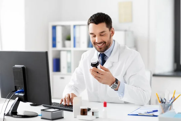 Male doctor with medicine and computer at hospital — Stock Photo, Image