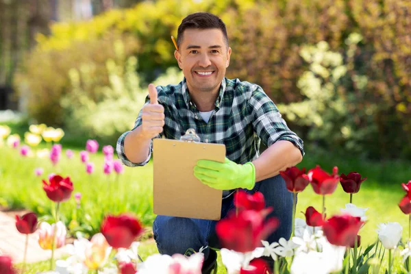 Homem com prancheta mostrando polegares para cima jardim — Fotografia de Stock