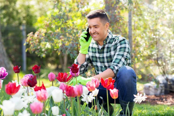 Homme avec des fleurs appelant sur smartphone au jardin — Photo