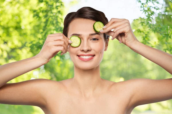 Mooie vrouw maken oogmasker van komkommers — Stockfoto