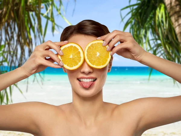 Femme faisant masque des yeux de tranches d'orange sur la plage — Photo