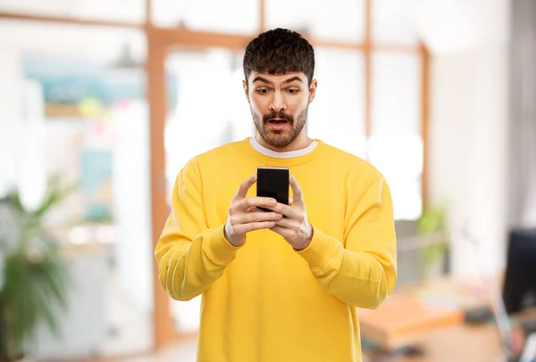 Verrast jongeman met smartphone — Stockfoto